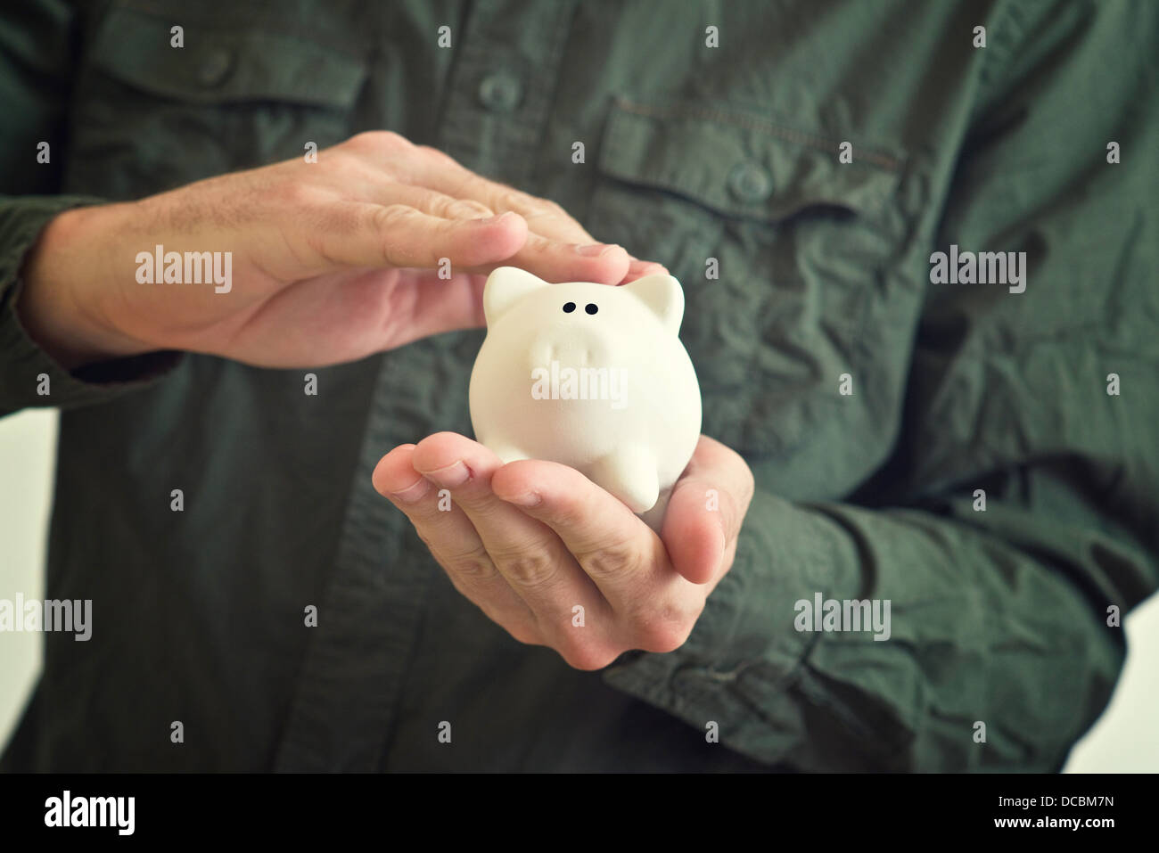 Hand schmiegt weißen Piggy Spardose mit Angst Blick in seine Augen. Stockfoto