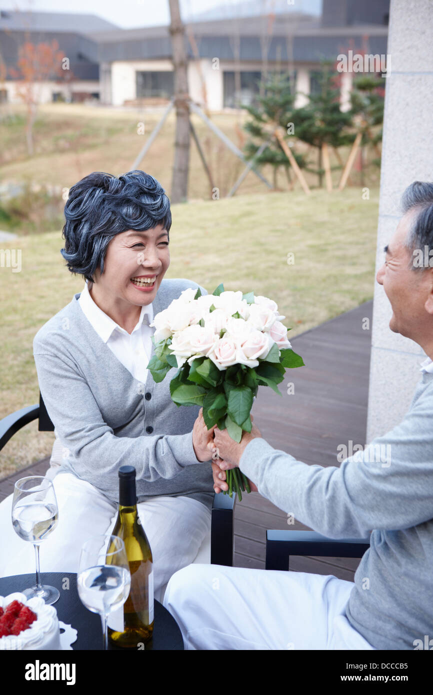 Mann mittleren Alters geben Blume Bundle zu seiner Frau in Jubiläum Stockfoto