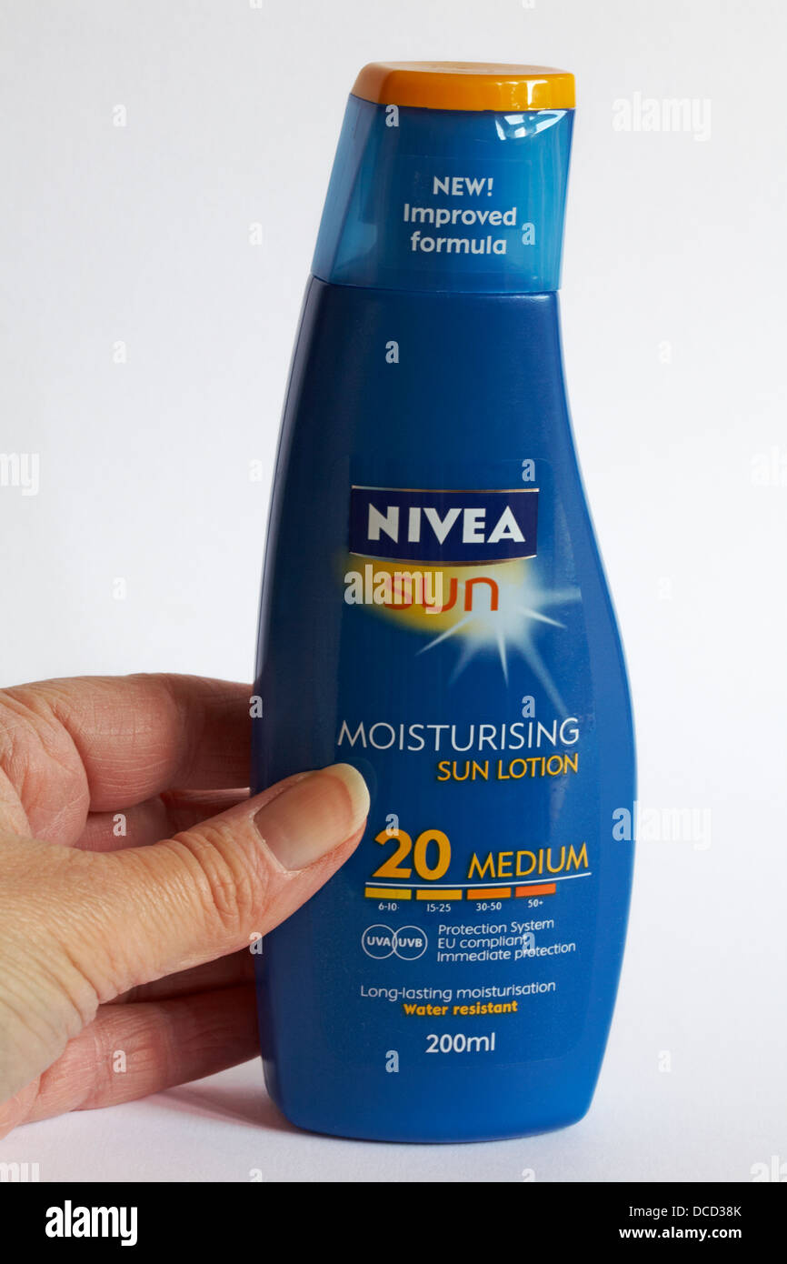 Greifen Sie nach der Flasche der feuchtigkeitsspendenden Sonnenlotion Nivea Sun Sonnencreme - Nivea LSF 20 Stockfoto