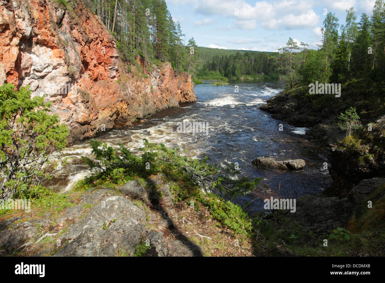 Oulankajoki Fluss fließt durch die Kuitaköngäs Stromschnellen unter einem Felsvorsprung der rote Fels in Oulanka-Nationalpark, Finnland. Stockfoto