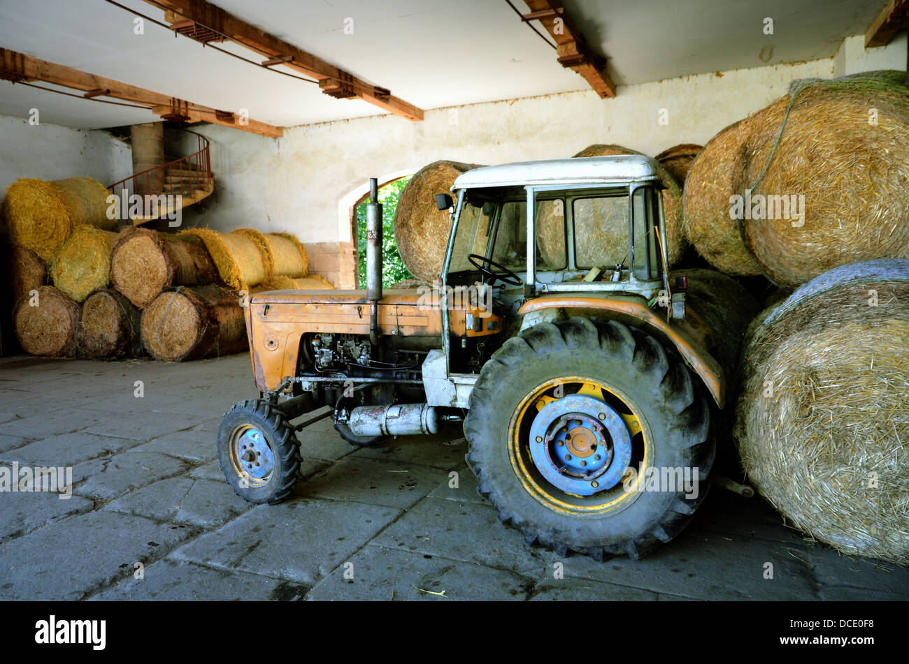 Rundballen aus Stroh mit Traktor Stockfoto