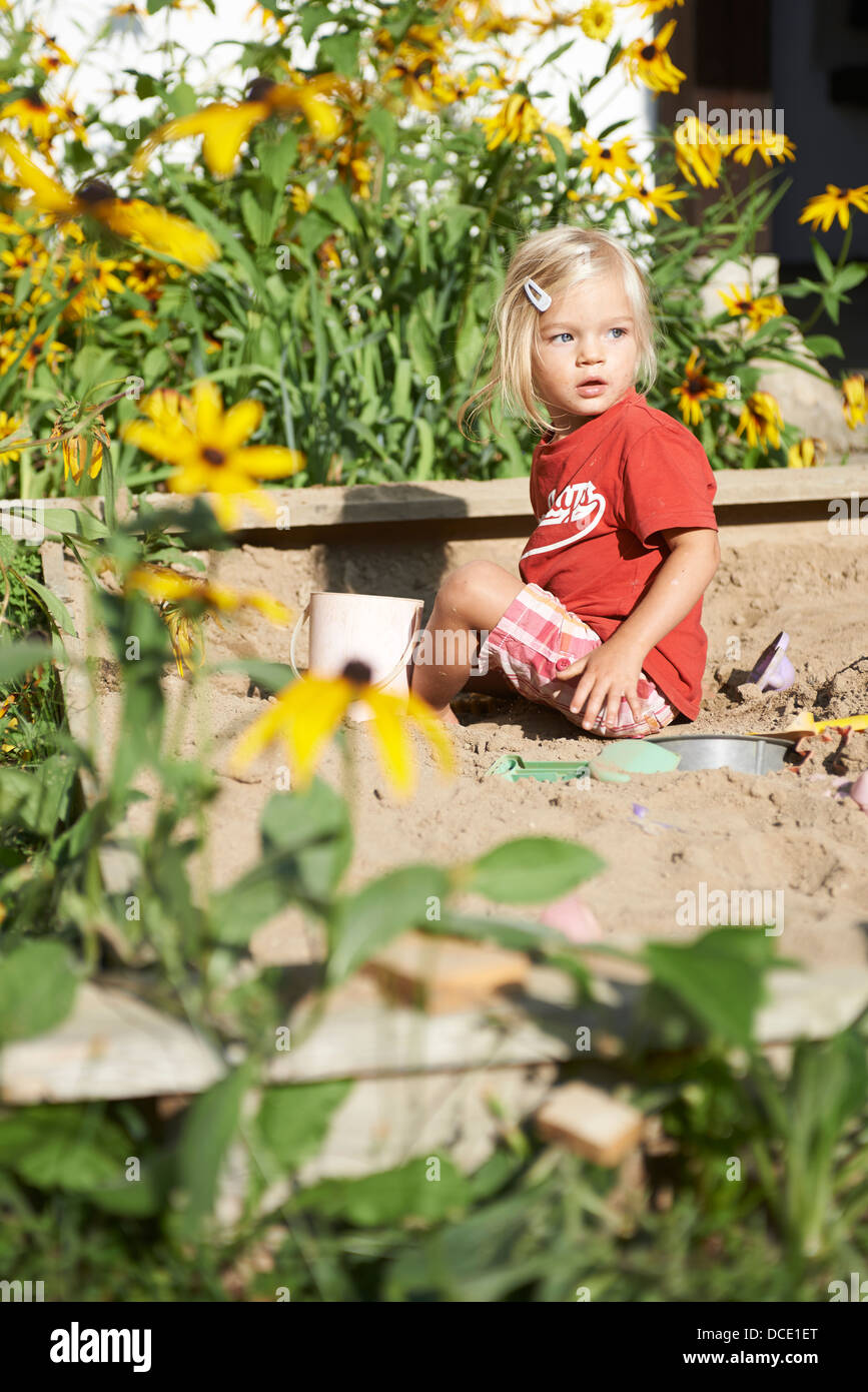 Kleines blondes Mädchen spielen im Sandkasten im Sommergarten Stockfoto