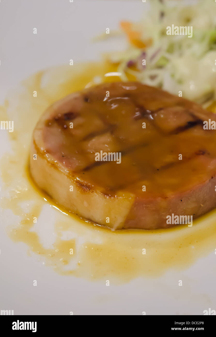 gebackener Schinken mit Soße Sauce auf weißen Teller mit frischem Salat serviert Stockfoto