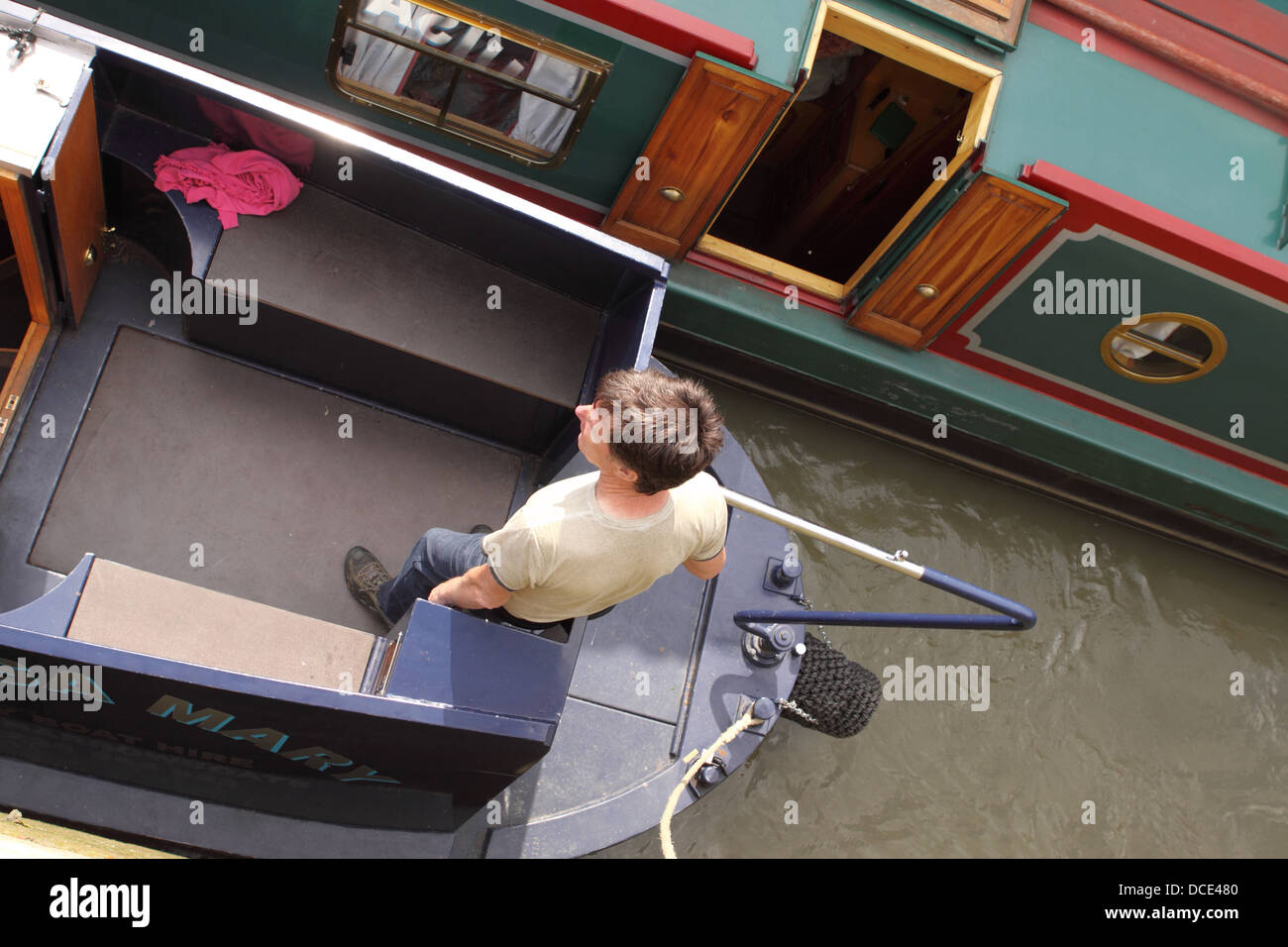 Kanal-Boot-Mann mit dem Ruderpinne auf einem engen Boot UK Stockfoto