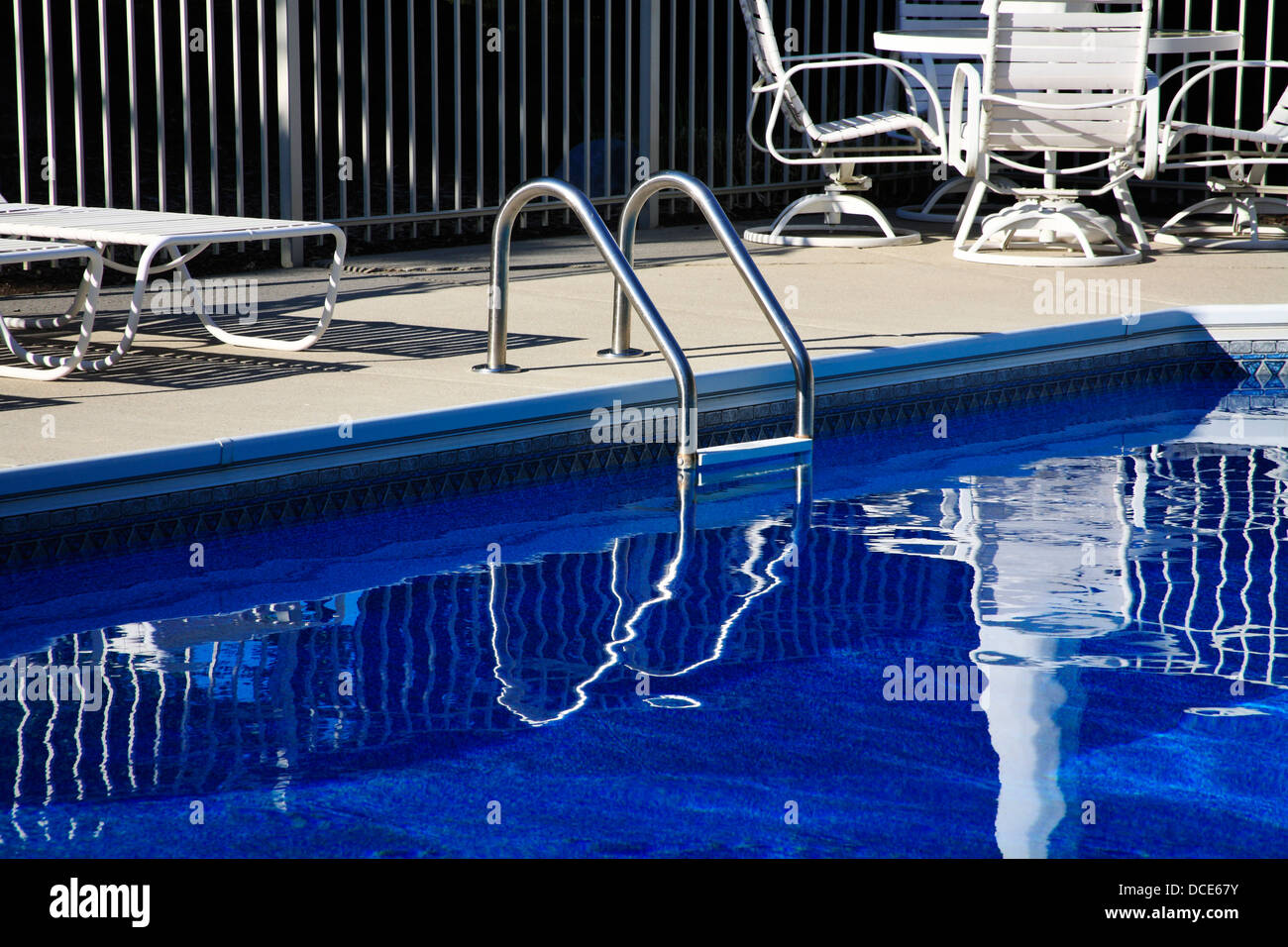 Ein Pool-Leiter und tiefblaue Schwimmbadwasser In symmetrische Reflexion an einem sonnigen Tag Stockfoto