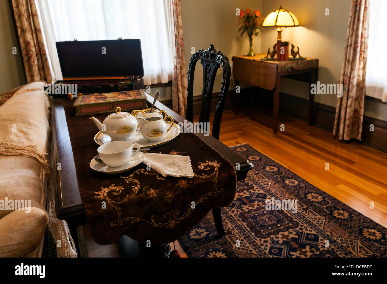 Tee-Service setzen auf Sofatisch im Zeitraum Wohnzimmer mit Perserteppich. Stockfoto