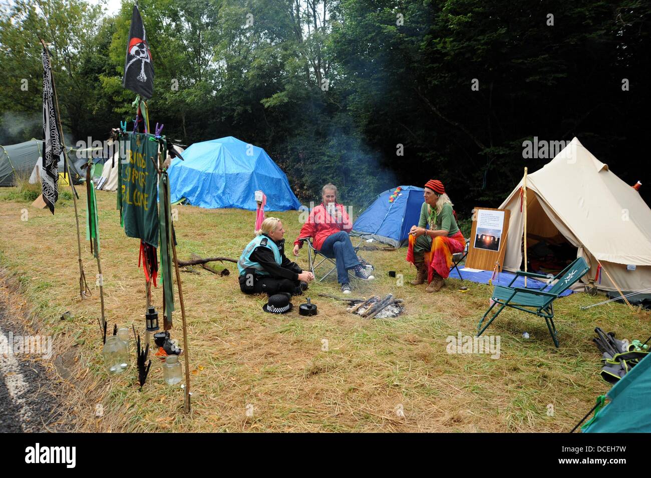 Balcombe Sussex UK 16. August 2013 - sammeln ein Polizei Liason Officer Chats mit Demonstranten neben einem Feuer als anti-Fracking-Aktivisten am Standort Cuadrilla in West Sussex Dorf der Balcombe wo die Firma Explorationsbohrungen durchführen. Tausende von Demonstranten werden voraussichtlich den Protest über das bevorstehende Wochenende beitreten Stockfoto