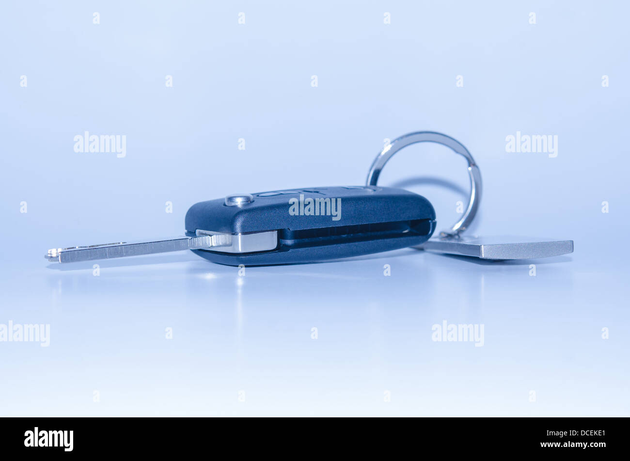 Blau getönten isoliert Fahrzeugschlüssel mit Schlüsselbund Schatten und Reflexion Stockfoto