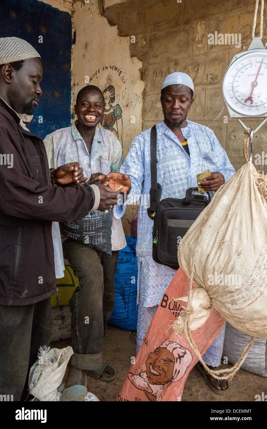 Cashew-Nuss-Käufer mit einem Gewicht von Nüssen, Verkäufer, Fass Njaga Choi, Gambia zu bezahlen. Stockfoto