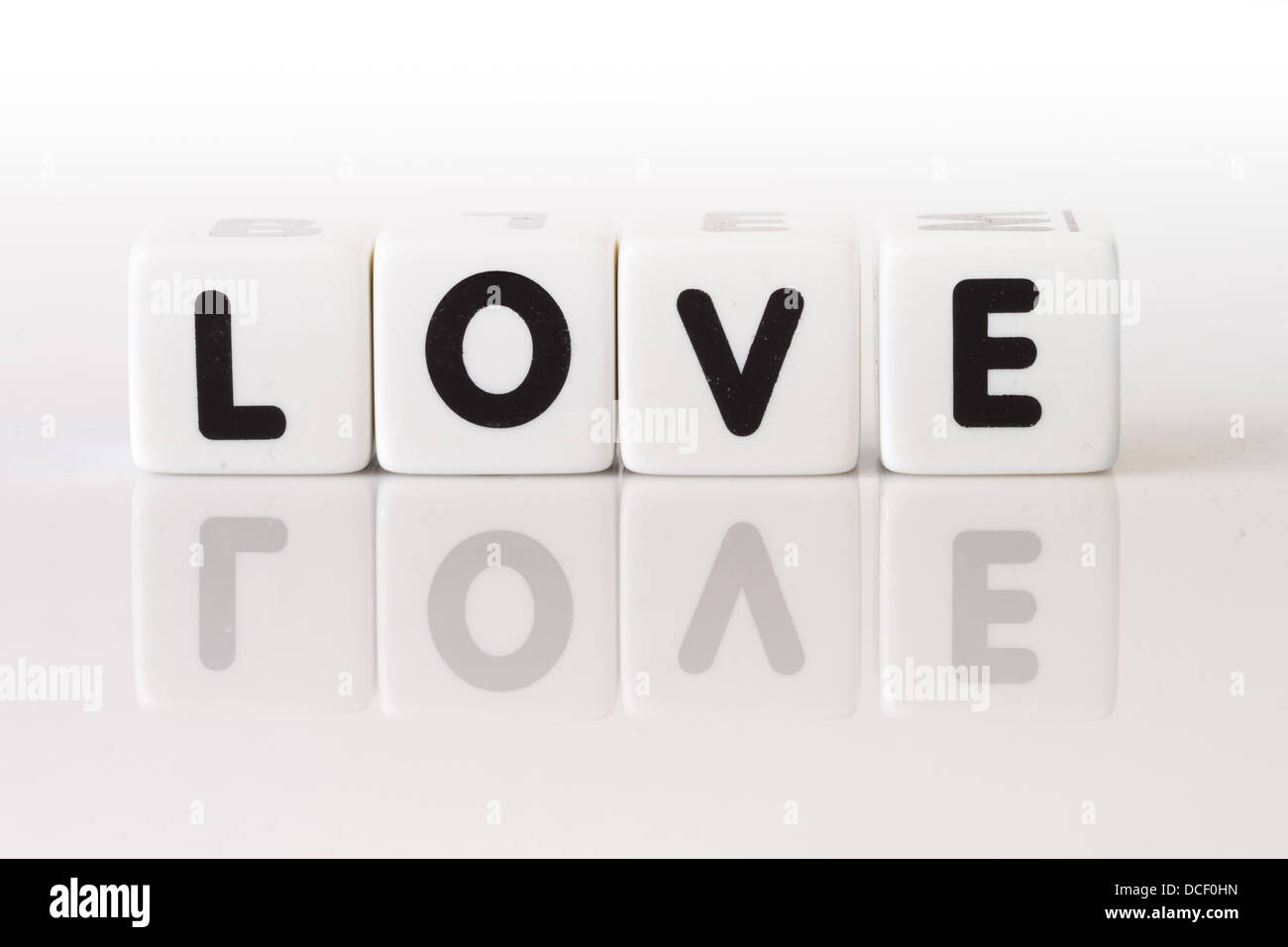 Das Wort Liebe buchstabiert in Spielwürfel auf isolierten weißen Hintergrund reflektiert. Stockfoto