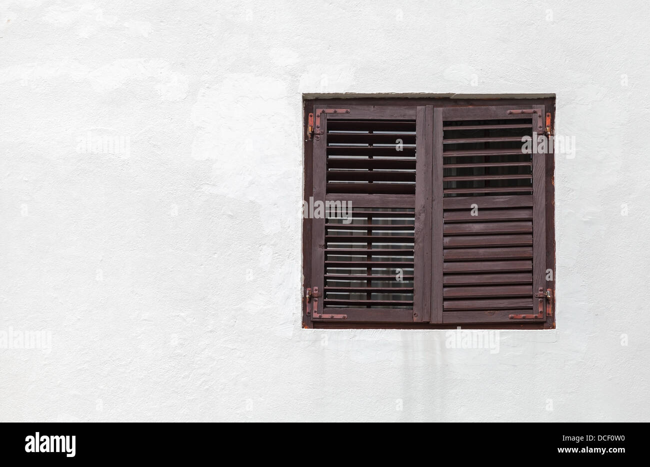 Holzfenster mit geschlossenen Jalousien in weiße Wand Stockfoto