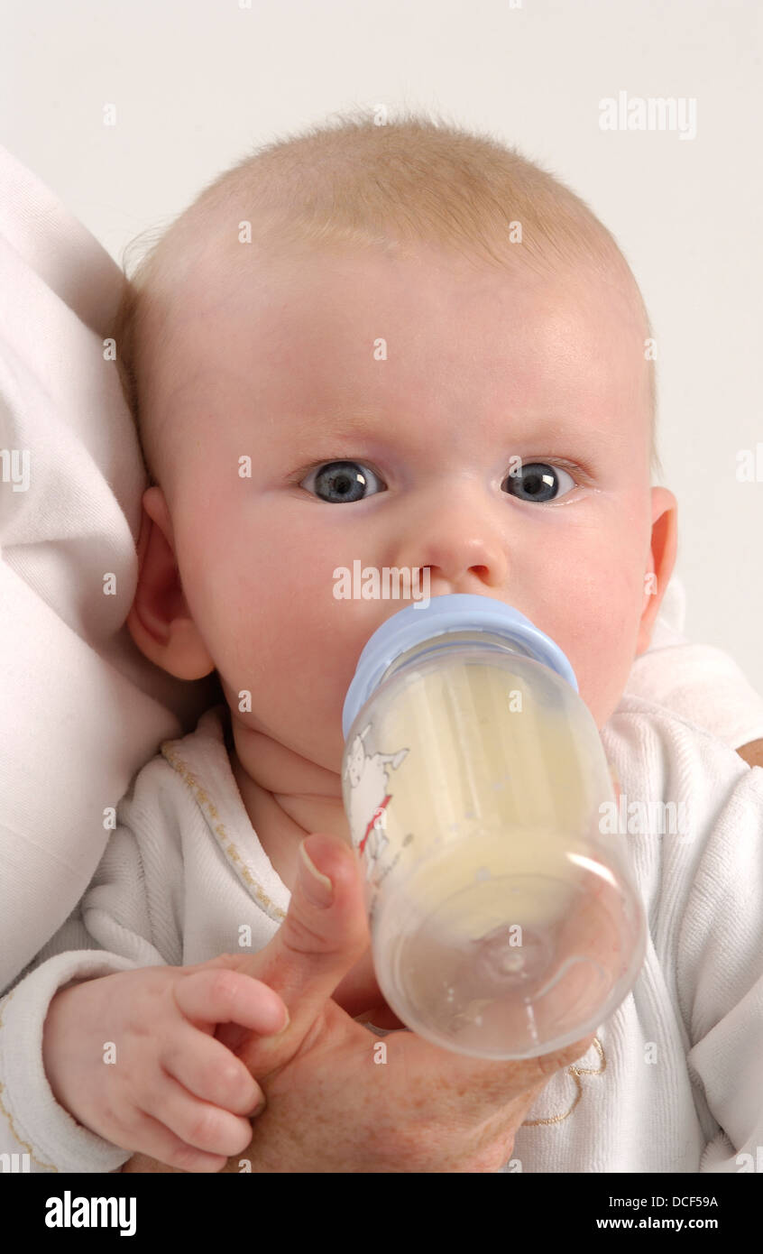 Babymädchen ist mit einer Flasche gefüttert. Stockfoto