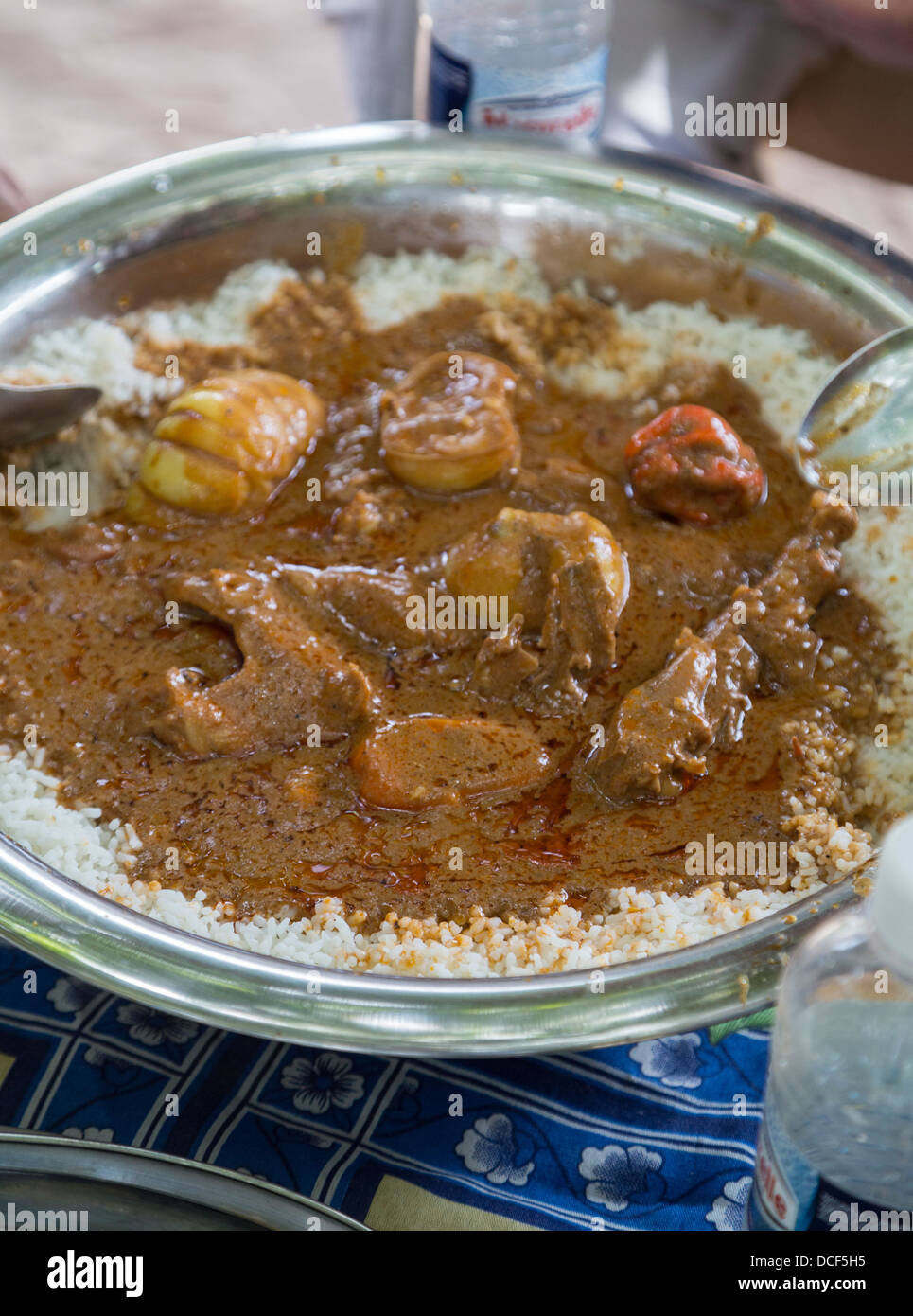 Cashew-Nuss-Eintopf mit Huhn, Paprika und Reis. Menschen rund um den Tisch essen aus einer gemeinsamen Schüssel.  Gambia. Stockfoto
