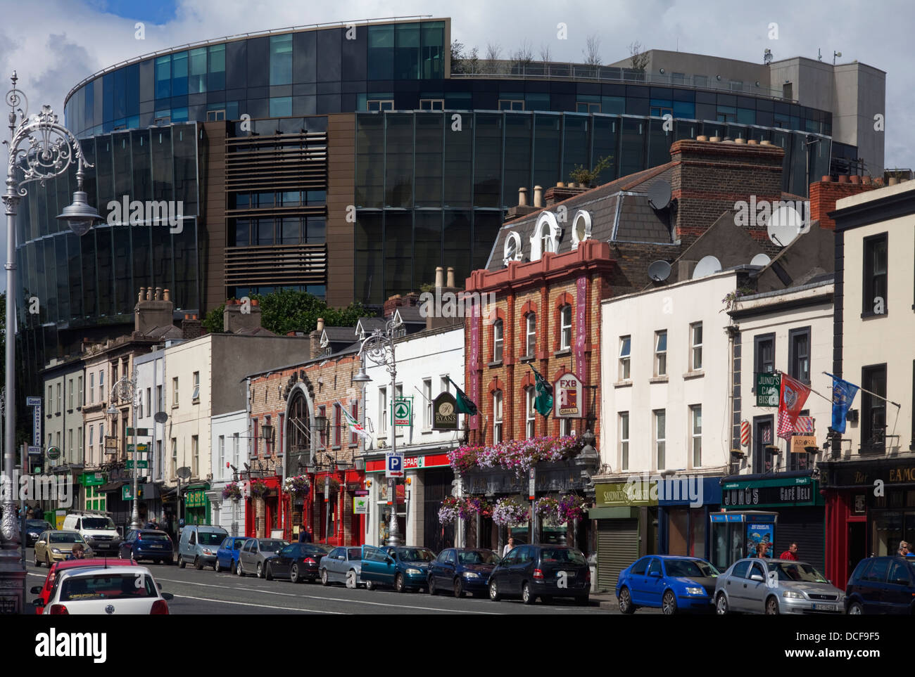 Geschäfte und Kneipen in der Pargate Street, in den Schatten gestellt durch die neuen Criminal Courts of Justice, in der Nähe von the Phoenix Park, Dublin City, Irland Stockfoto