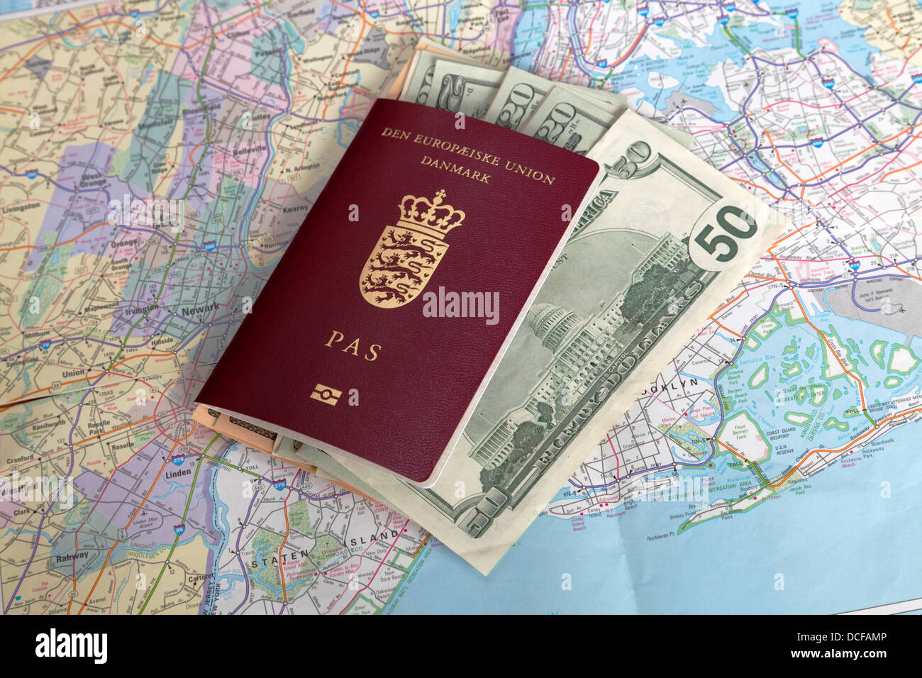 Einen dänischen Reisepass mit US-Dollarnoten auf einer Karte von New York City Stockfoto