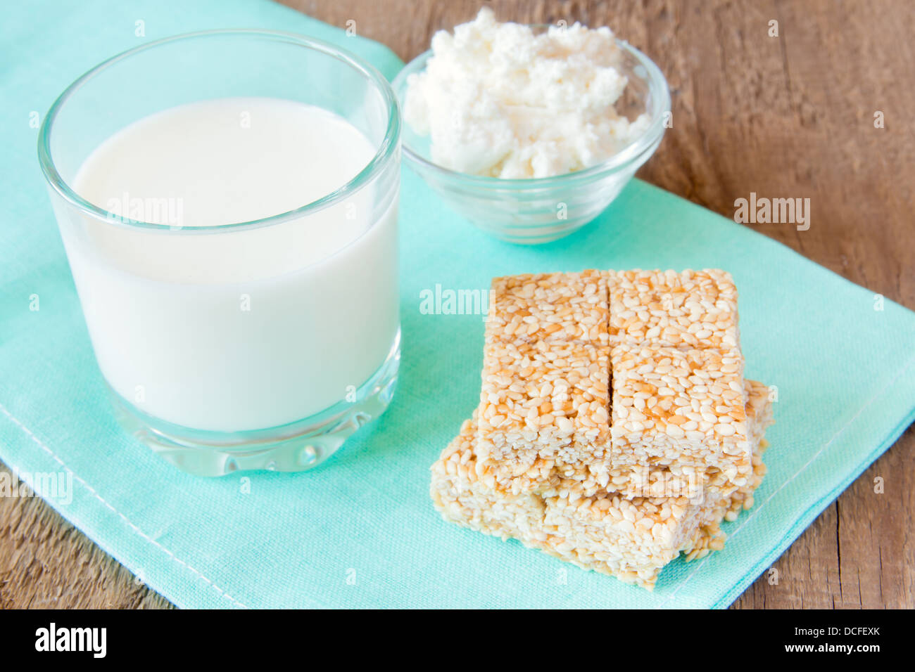 Kalzium-Produkte-Set: Milch, Sesam, Hüttenkäse auf Serviette und Holztisch, Nahaufnahme, Horizontal Stockfoto