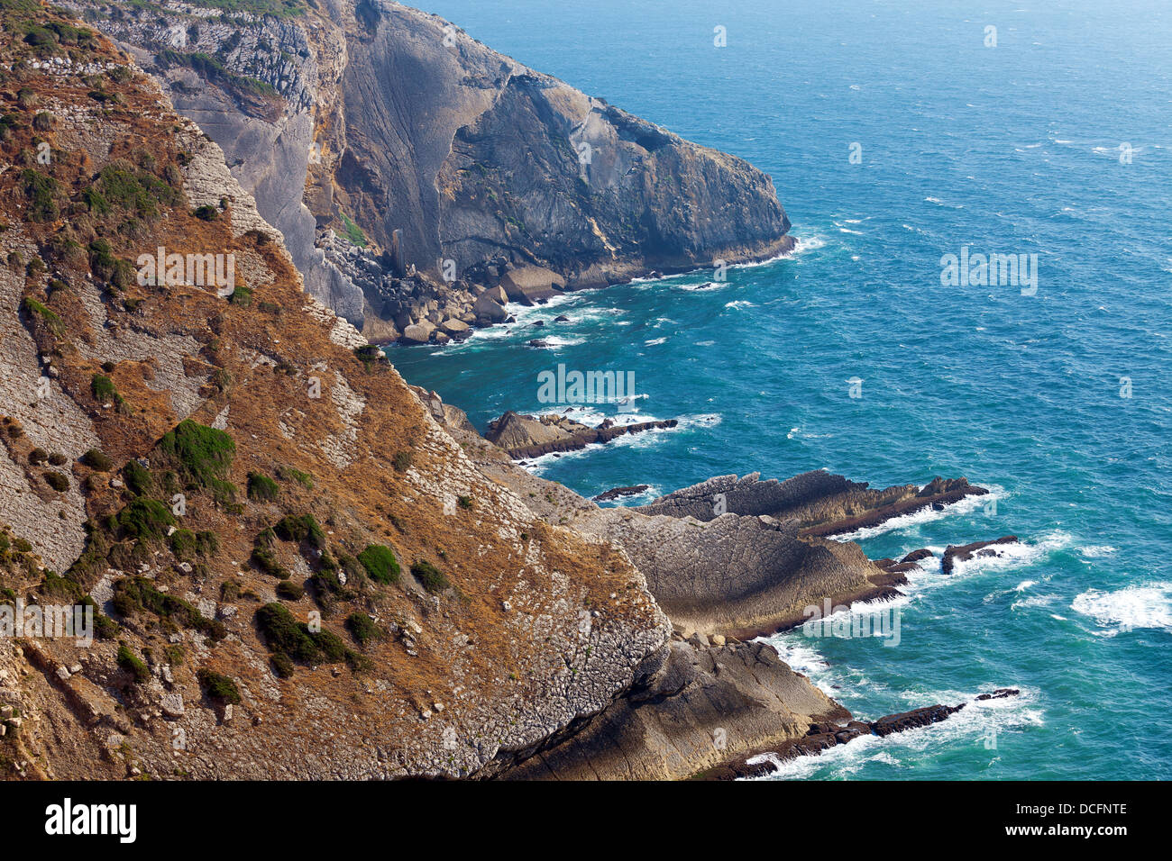 Blick auf eine zerklüftete Küste mit steilen kargen Klippen fallen nach unten auf eine felsige Küste mit Wellen Stockfoto