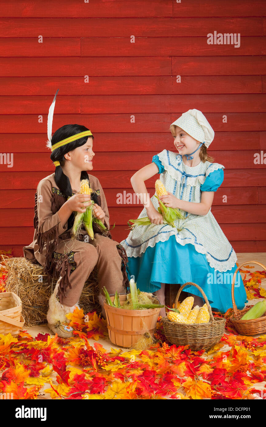 Zwei Kinder In Kostümen schälen Mais um die Ernte für Thanksgiving zu feiern; Drei Hügel, Alberta, Kanada Stockfoto