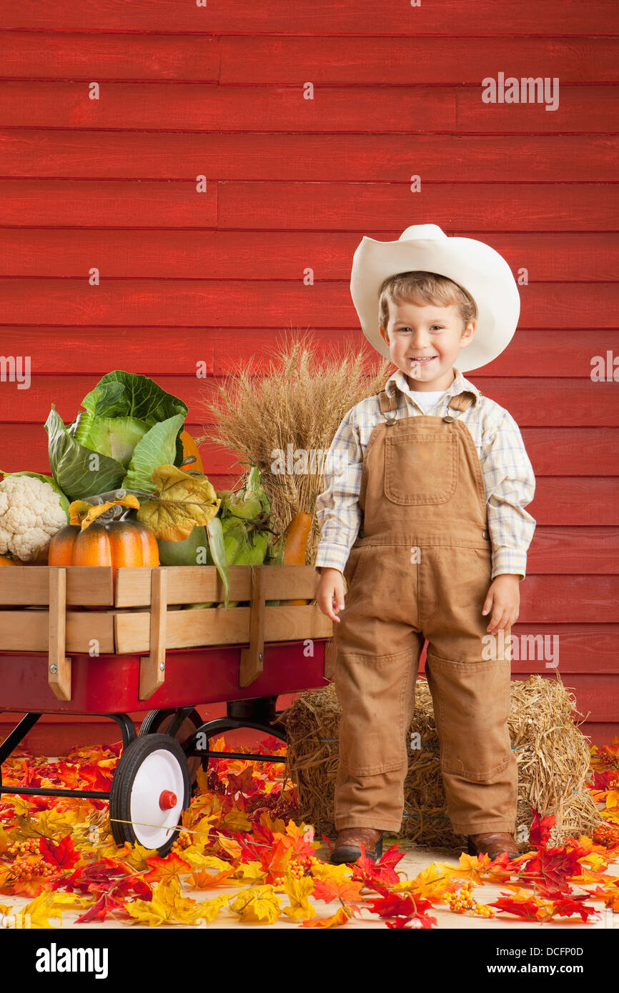 Ein Junge gekleidet wie ein Bauer mit einem Wagen voller Produkte; Drei Hügel, Alberta, Kanada Stockfoto