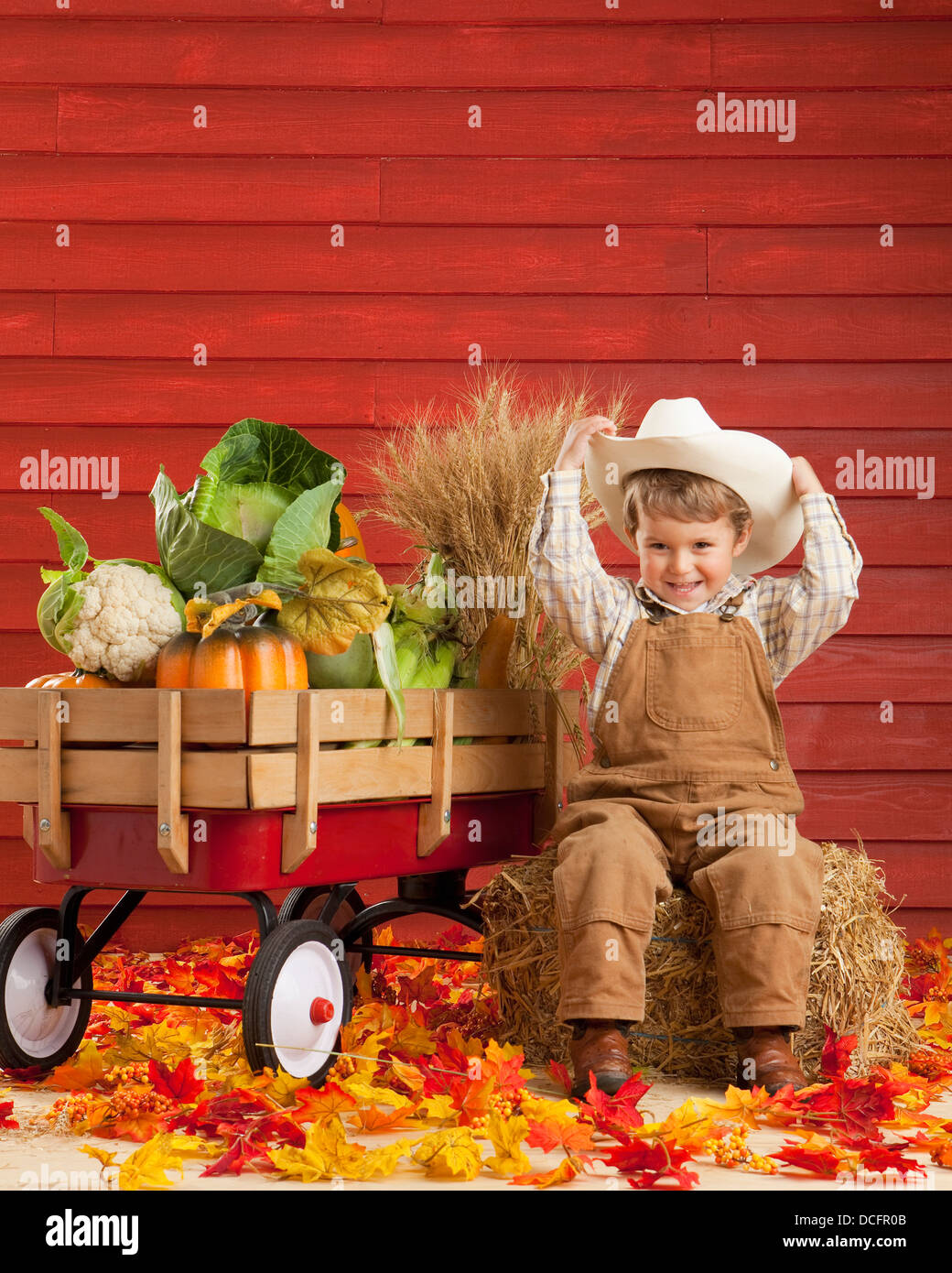 Ein Junge gekleidet wie ein Bauer mit einem Wagen voller Produkte; Drei Hügel, Alberta, Kanada Stockfoto