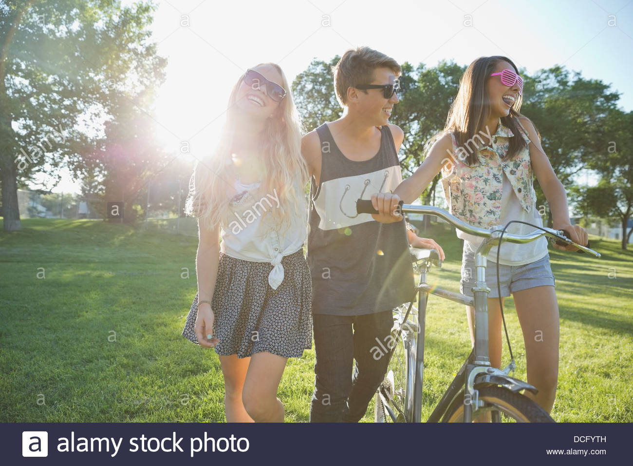 Glücklich Teenager Freunden mit dem Fahrrad, zu Fuß im park Stockfoto