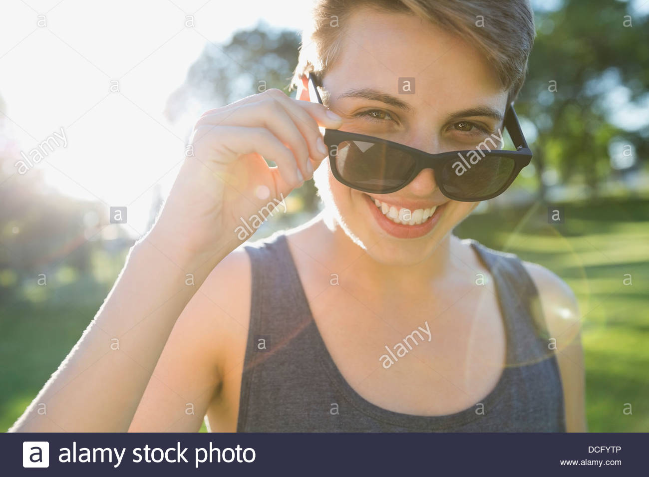Porträt des Lächelns Teen peeking über Sonnenbrillen Stockfoto