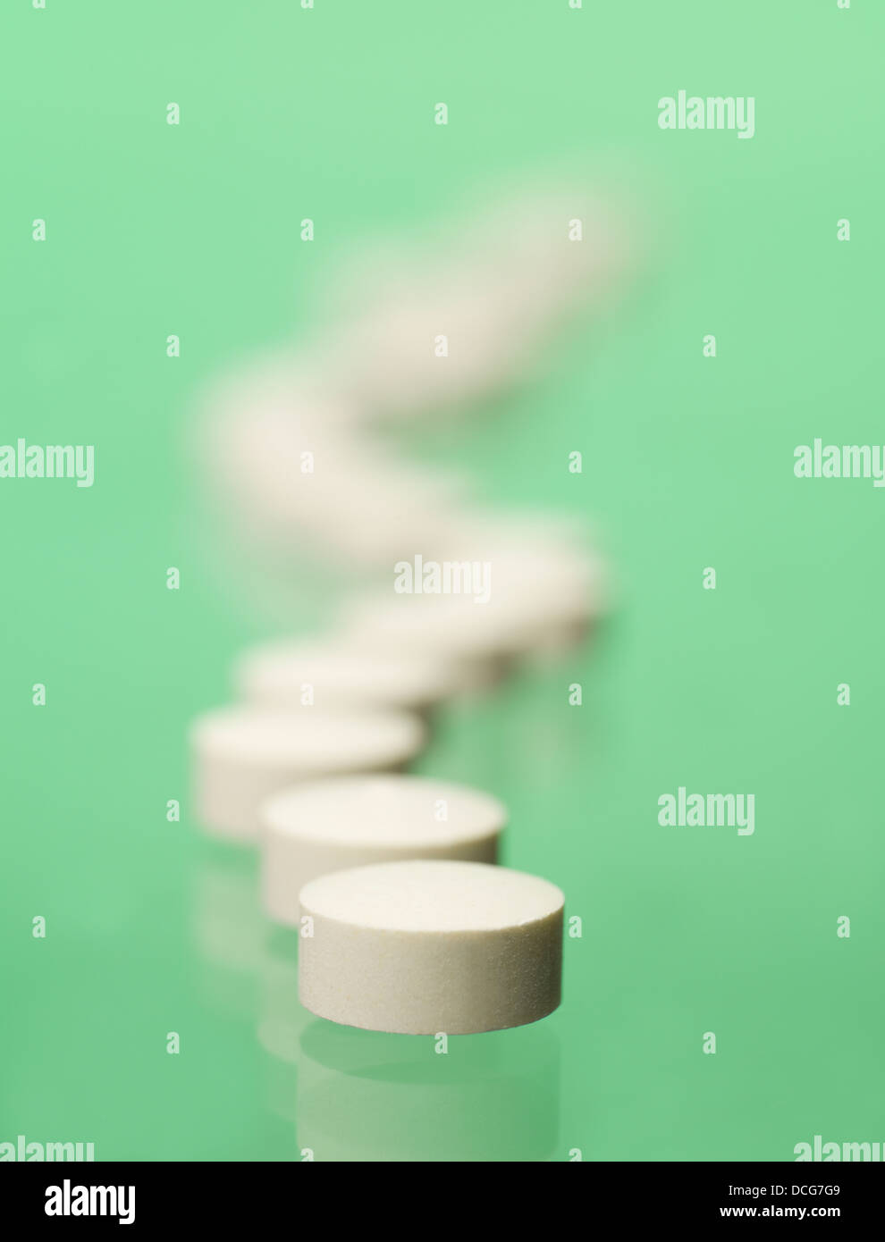 Pillen in Folge auf grünem Hintergrund Stockfoto
