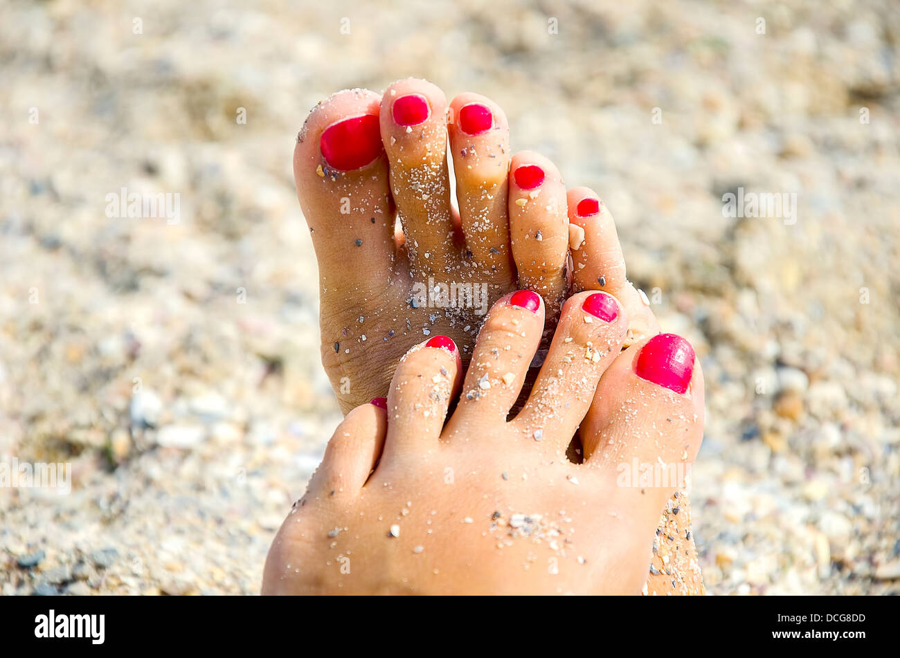 Frau die Füße mit roten Zehennägel im sand Stockfoto