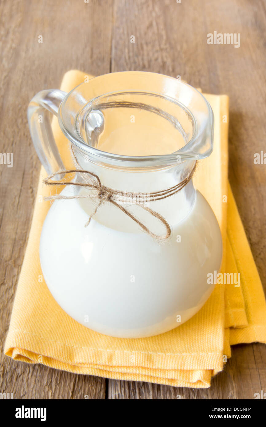 Milch im Glas auf Naprin und rustikalen Holztisch, vertikal, Textfreiraum Stockfoto