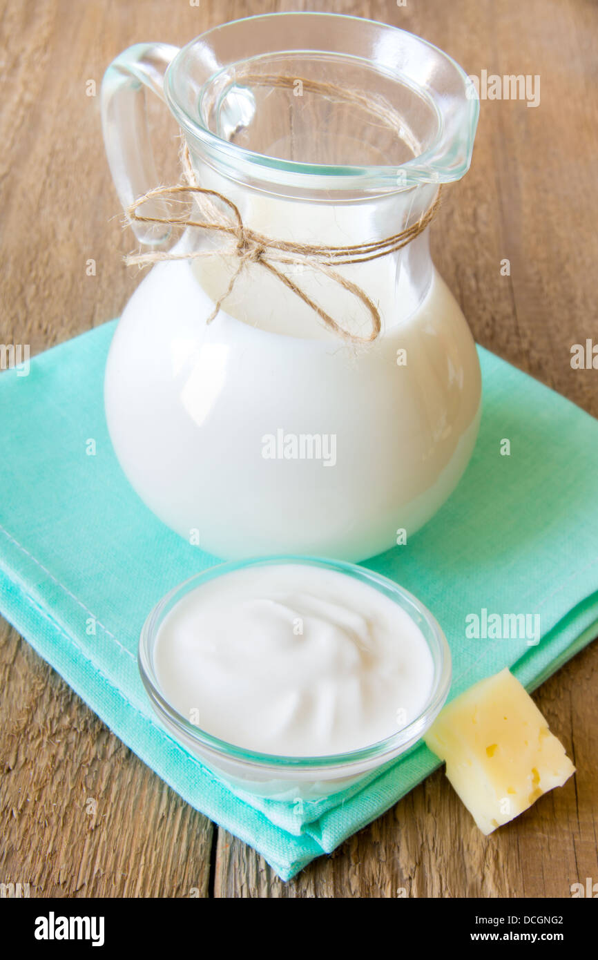 Kalzium-frische Milchprodukte-Set: Milch, Sauerrahm, Käse auf Serviette und Holztisch, Nahaufnahme, vertikale Stockfoto
