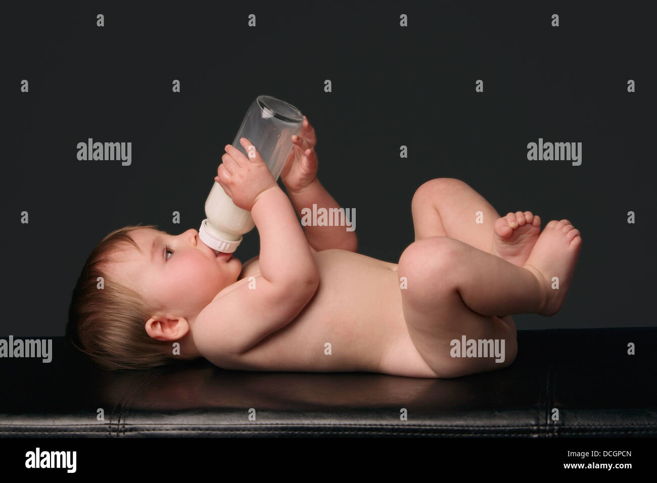 Nackten Baby legen und seine Trinkflasche Stockfoto