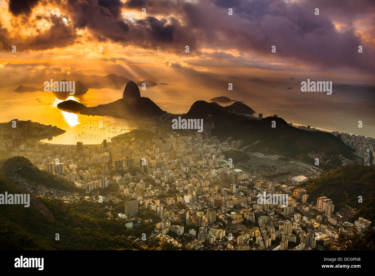 Von Corcovado aus entfaltet sich ein Stadtbild bei Sonnenaufgang über Rio de Janeiro, mit dem Sugarloaf Mountain und Botafogo Bay im Glanz des goldenen Lichtes der frühen Morgenröte Stockfoto