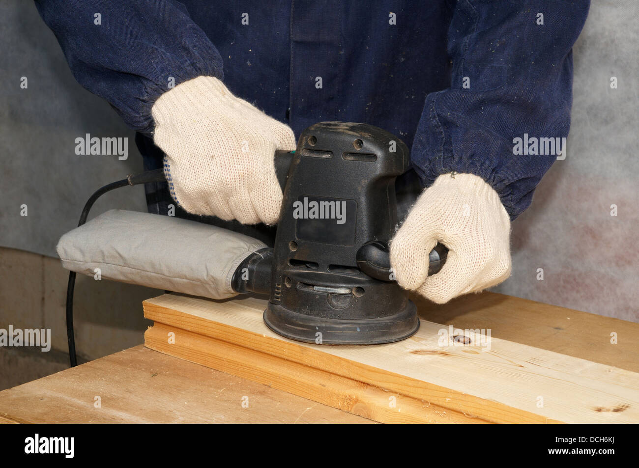 Die Arbeitskraft poliert Holzbrett mit elektrischen Schleifer Stockfoto
