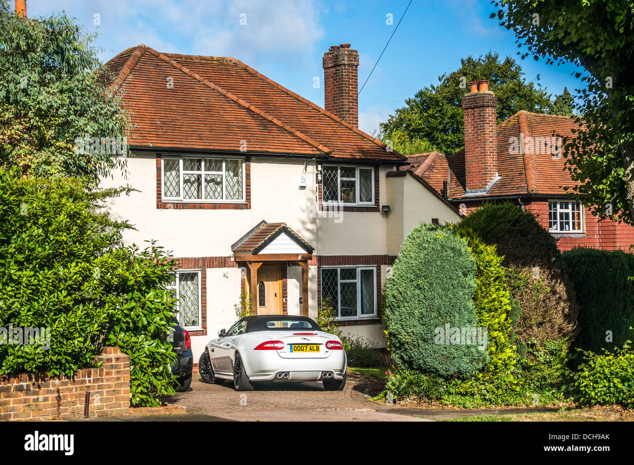 Ein gehobenes Zeitraum freistehendes Haus mit dem Auto draußen geparkt, in Surrey, England, UK. Stockfoto