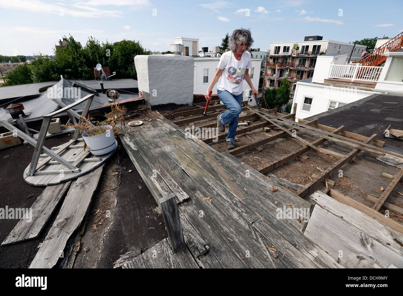 Eine Frau entfernt einen alten Holz-Deck aus einem Hausdach in Boston, Massachusetts Stockfoto