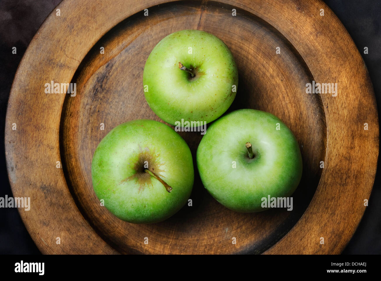 Drei grüne Äpfel in Holzplatte Stockfoto