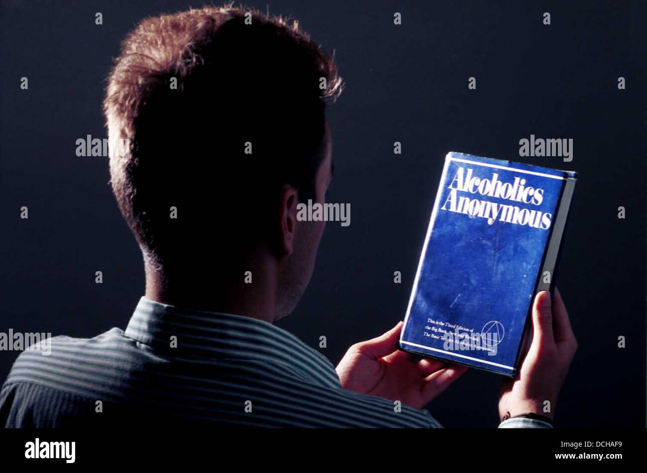 Ein Alkoholiker liest die grundlegenden Text oder großen Buch der Anonymen Alkoholiker. Stockfoto