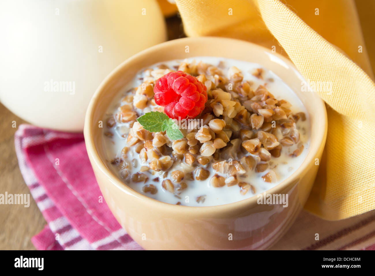 Buchweizengrütze mit Milch auf weiße Serviette und Holztisch, Nahaufnahme, horizontale. Natürliche Bio vegetarisches Essen (Frühstück Stockfoto