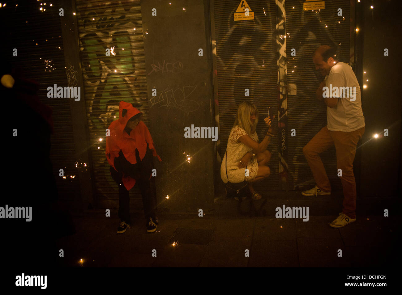 Barcelona, Spanien. 18. August 2013. 18. August, 2013-Barcelona, Spain.Viewers die Kohlen zu schützen und zu fotografieren. Correfocs, eine alte katalanische Tradition, wo Menschen verkleidet als Teufel Feuerwerkskörper und Fackeln sprengen, nehmen Sie Teil an den Feierlichkeiten zum Sant Roc Festival im gotischen Viertel von Barcelona. Bildnachweis: Jordi Boixareu/Alamy Live-Nachrichten Stockfoto