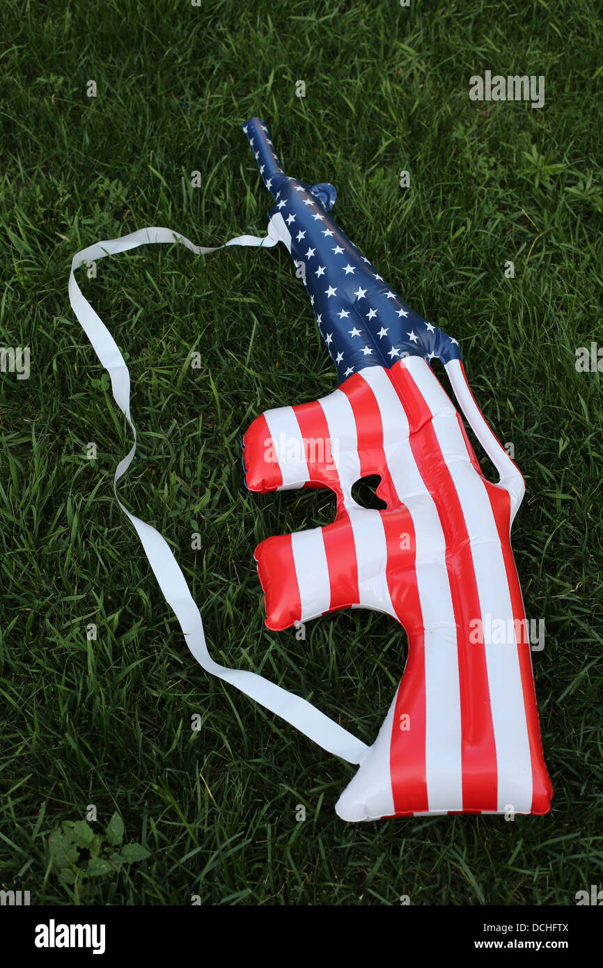 Ein aufblasbares Spielzeug, geformt wie eine Waffe, die aus einer amerikanischen Flagge gemacht. Stockfoto