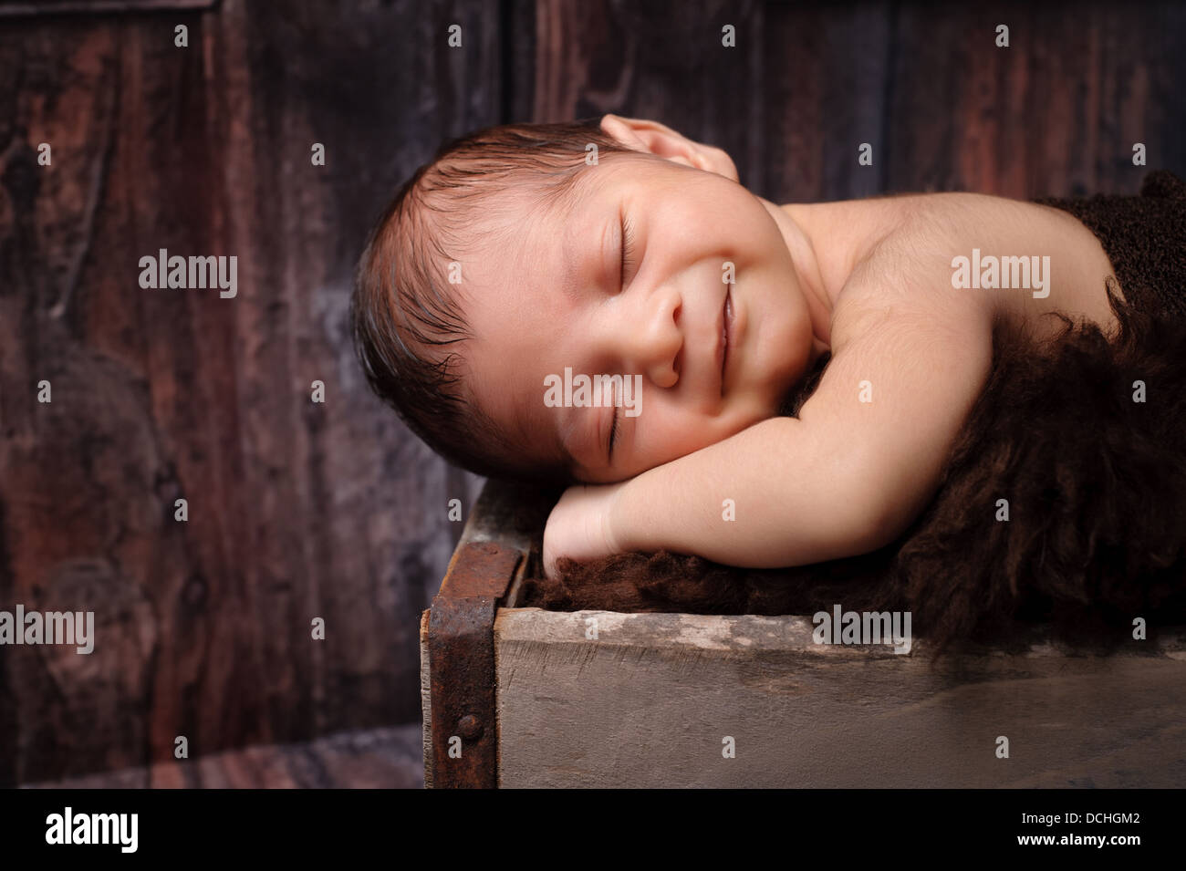 Lächelnd neugeborenen Jungen schlafen in einer rustikalen Kiste Stockfoto