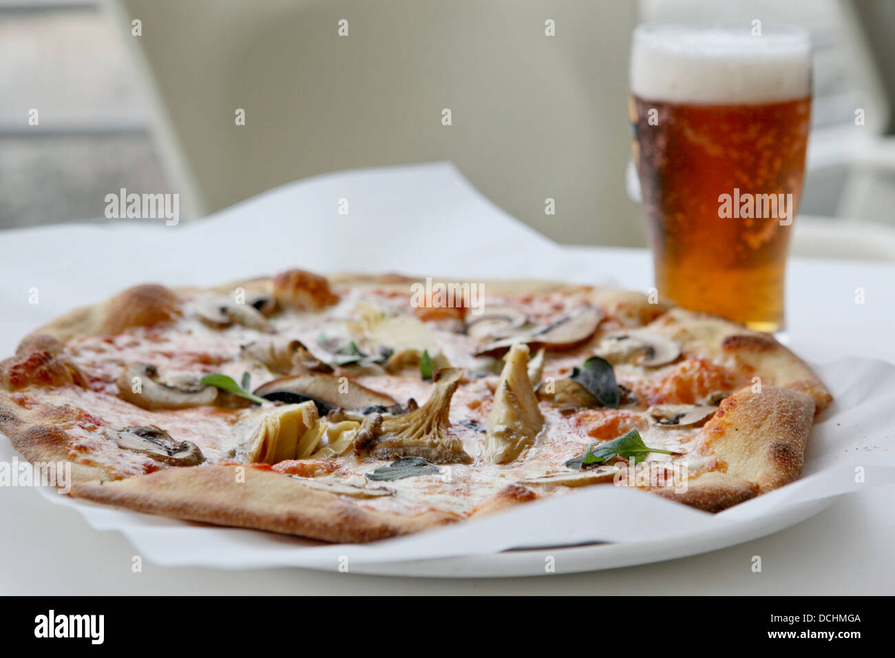 Frisch gebackene Champignons Pizza serviert mit Bier Stockfoto
