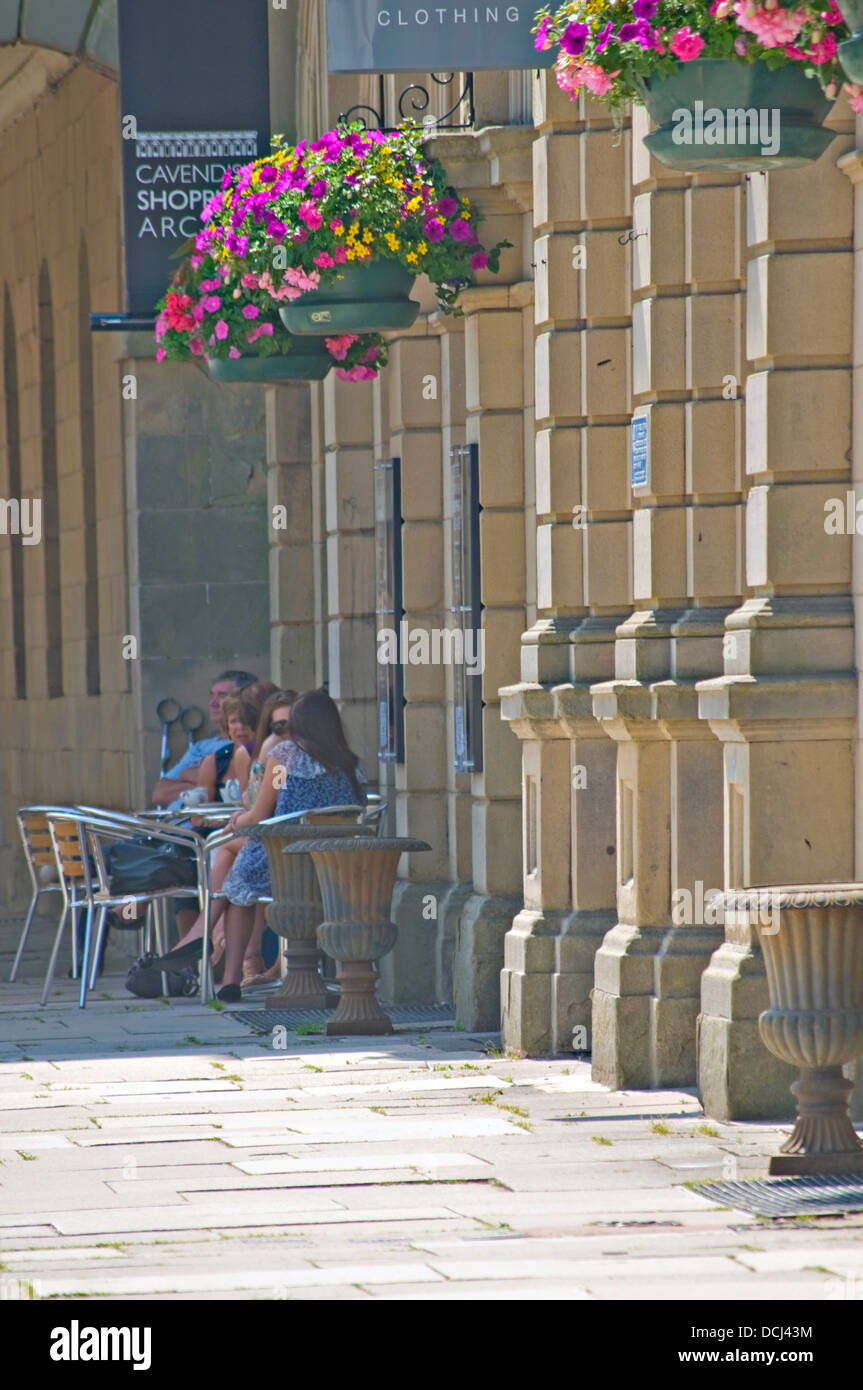 Porträt von einigen Menschen genießen die Sonne auf einem Café Pflaster Tisch in Buxton Town Centre, Großbritannien. Stockfoto