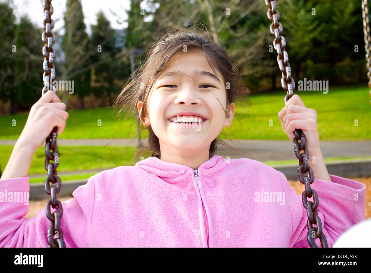 Glückliche kleine Mädchen lächelnd auf einer Schaukel im park Stockfoto