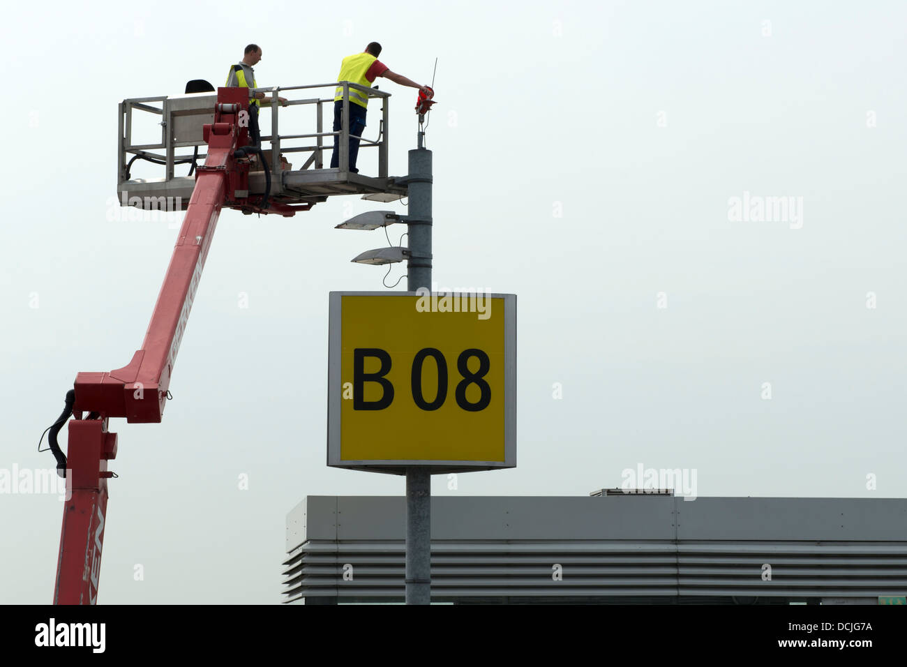 Arbeiter in einer Hubarbeitsbühne ersetzen Glühbirnen am Flughafen Düsseldorf Deutschland Stockfoto