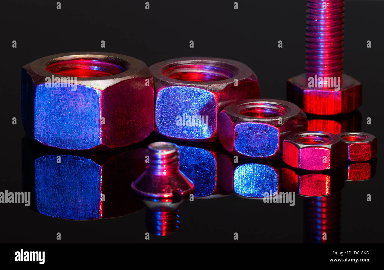 einige rot und blau beleuchteten Muttern und eine Schraube in Schwarz Reflektierende Rückseite Stockfoto