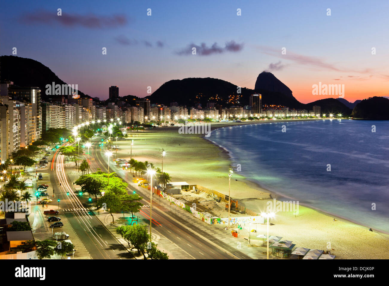Sonnenaufgang am Strand der Copacabana, Rio De Janeiro, Brasilien. Atlantica Avenue, Zuckerhut im Hintergrund. Stockfoto