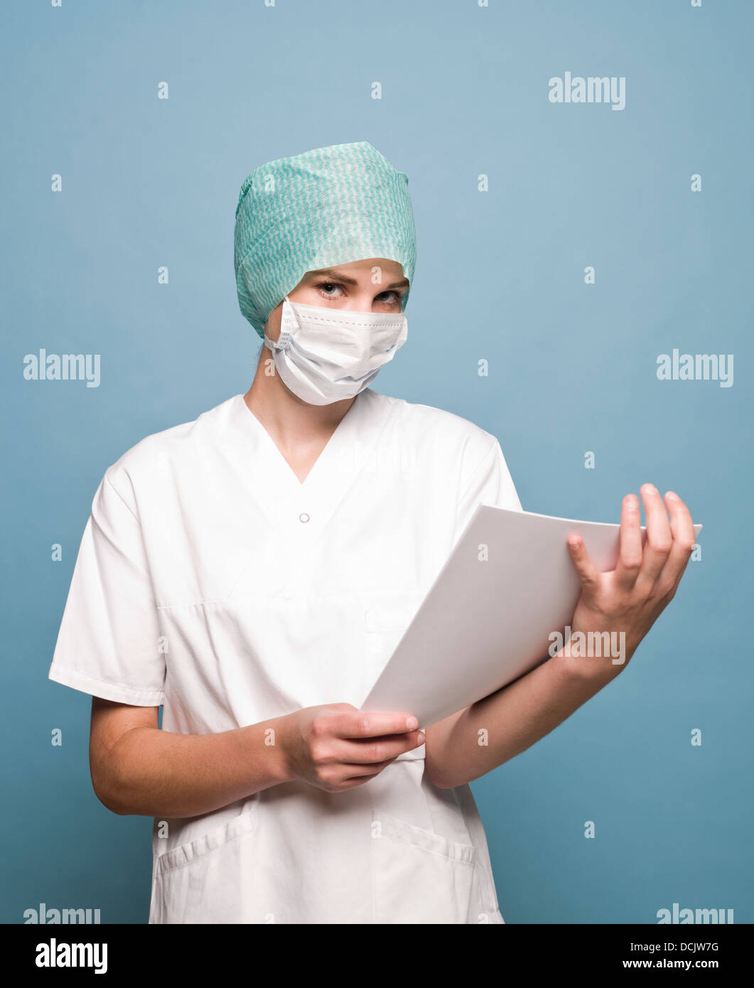Krankenschwester mit Mundschutz und eine Zeitschrift, die vor der Kamera Stockfoto