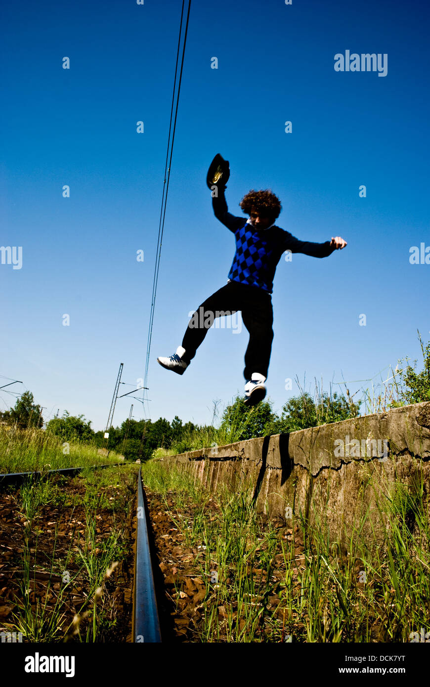 Junge modische Mann springt vom Bahnsteig auf der Bahn Stockfoto