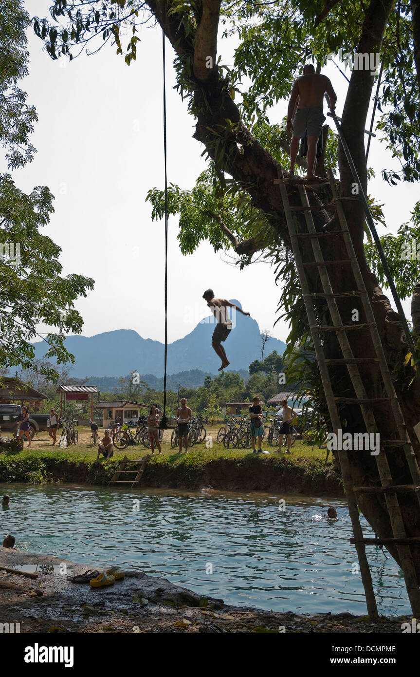 Vertikale Ansicht eines Touristen, der Sprung von einem Baum in der blauen Lagune entlang des Nam Song Flusses in der Nähe von Vang Vieng. Stockfoto